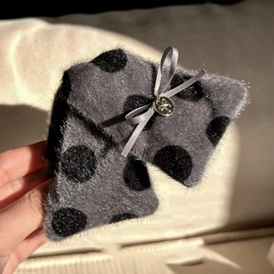 Détail de la pince à cheveux en peluche à pois avec nœud et pendentif floral en métal doré