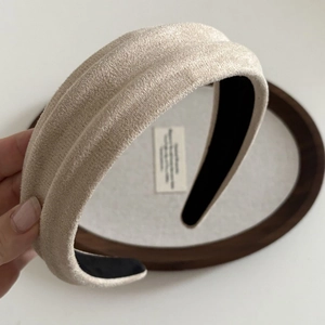 Detail view of the wide beige suede headband showing non-slip lining and thick texture