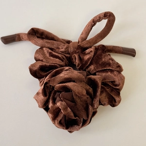 Vue détaillée de la texture du chouchou en velours marron foncé et du ruban de coiffage