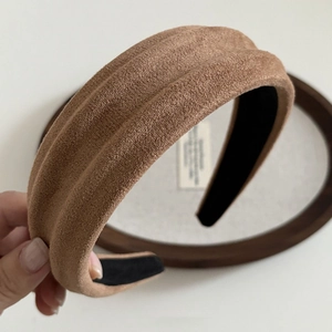 Close-up of suede texture on dark camel padded headband with non-slip inner lining