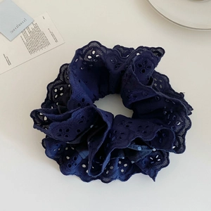 Detailed close-up of navy blue double-layered lace hair scrunchie on a white surface