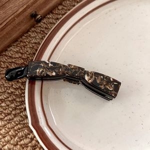Detailed view of banana hair clip with retro marble texture on a ceramic plate