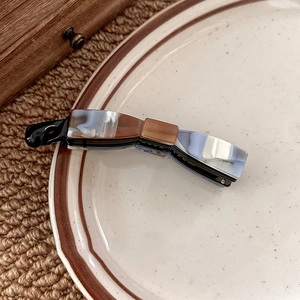 Detail view of a marble pattern bow banana clip hair accessory in a ceramic plate