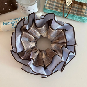 Detail view of a double-layered plaid scrunchie with blue fabric and brown stitching edge