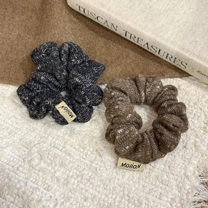Detail of two chunky knit hair scrunchies with Mollon labels in neutral earth tones
