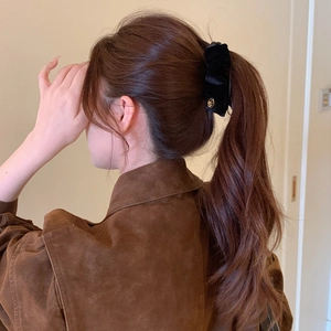 Elegant black velvet scrunchie with gold buckle on a ponytail hairstyle