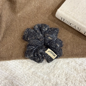 Detailed close-up of dark charcoal tweed knit scrunchie with a stylish side fabric label