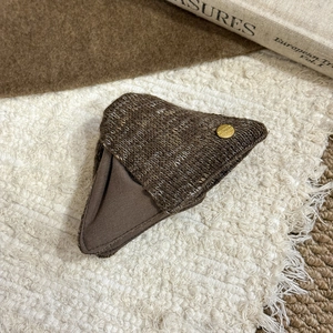 Brown knit triangle mini pouch with gold button and soft winter atmosphere background