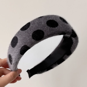 Close-up of retro dark gray plush headband with black polka dots and soft texture