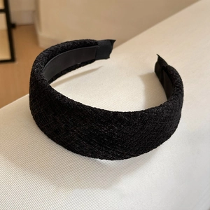 Détail de la texture en tissu tweed noir et du design rembourré épais de ce serre-tête