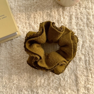Close-up of ginger knit scrunchie with rib texture and dark lock-edge detail