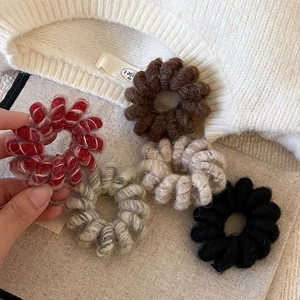 Cinq chouchous élastiques en peluche type cordon de téléphone sur fond tricoté
