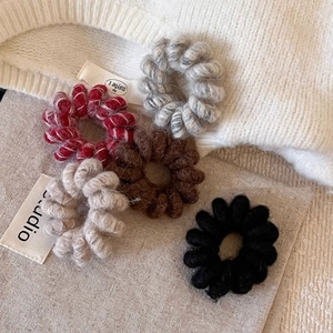 Cinq chouchous spirale en peluche de couleurs variées sur tissu en maille douce