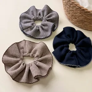 Three-piece set of knitted oversized scrunchies in brown, grey and blue with wave edges