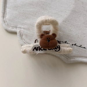 Detalle de oso de peluche marrón en pinza para el pelo blanca esponjosa con etiqueta