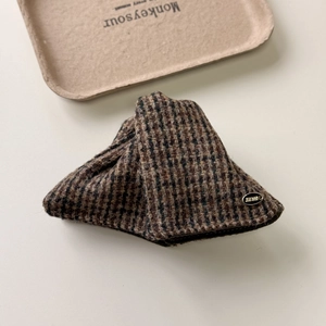 Detailed close-up of brown plaid fabric hair claw clip with a Lucky metal nameplate