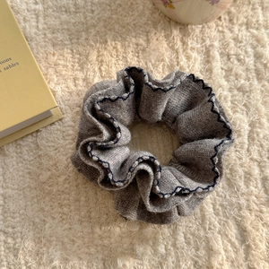 Detail of grey knitted hair scrunchie with blue scalloped edges on soft fleece texture