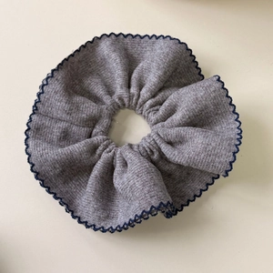 Detail of grey knitted scrunchie with dark wavy edges and vertical ribbed texture