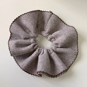 Detailed macro view of the double-layer knitted scrunchie with brown wavy edge detail