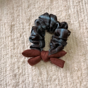 Detailed view of plaid checkered scrunchie with a brown velvet bow on a soft background