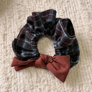 Detailed view of plaid scrunchie with blue and brown check patterns and rust red bow