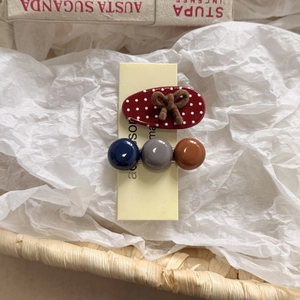 Close-up of a red polka dot bow hair clip and a three-color beaded side hairpin set