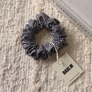 Détail d'un chouchou en tissu à carreaux noir et blanc avec une étiquette de marque
