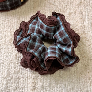 Detailed close-up of retro blue and brown plaid scrunchie with delicate lace embroidery edge
