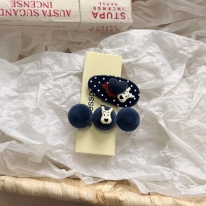 Detailed view of navy plush pom-poms and cartoon dog motifs on stylish hair clips