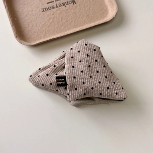 Detailed close-up of handmade cream knit hair clip with black polka dots in a triangle design