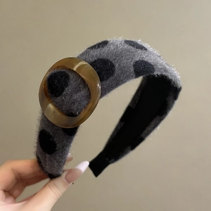 Detailed shot of grey plush headband with black polka dots and amber decorative buckle
