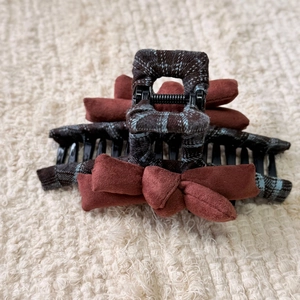 Detailed close-up of retro plaid hair claw clip with multiple plush reddish-brown bows