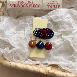 Close-up of navy polka dot bow clip and colorful ball hairpins in a rustic gift basket