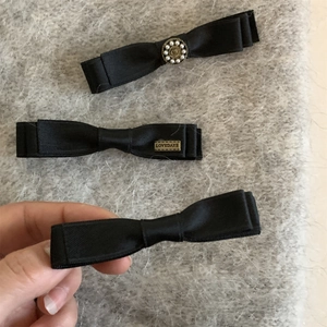 Trois élégantes barrettes à nœuds noirs avec perles sur fond en peluche gris doux