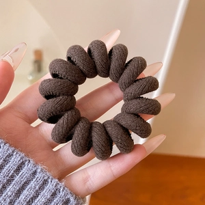 Gros plan d'un chouchou spirale marron avec une texture en sergé tenue à la main