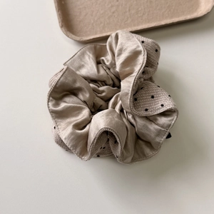 Close-up of elegant beige satin and polka dot knit hair scrunchie with layered texture
