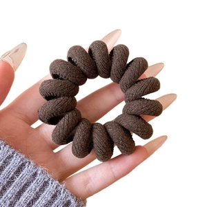 Élastique à cheveux spirale marron foncé avec texture tissée sur un fond blanc épuré