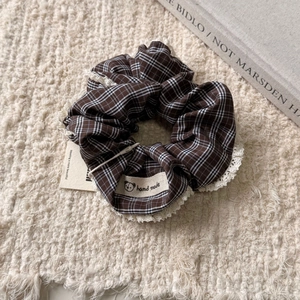 Détail d'un chouchou à carreaux marron avec dentelle et étiquette faite à la main