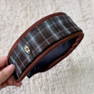 Close-up of retro blue and brown plaid scrunchie with a gold metal R-logo detail