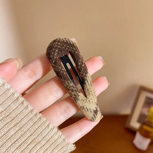 Detailed macro view of the vintage brown plaid fabric texture on a metallic BB hair clip