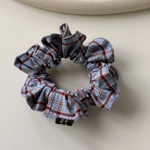 Détail d'un chouchou à carreaux bleus et rouges avec étiquette logo dorée sur tissu