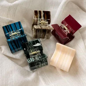 Detailed close-up of five acetate hair claw clips featuring various marble and tortoiseshell patterns