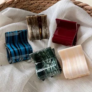 Set of five retro acetate claw clips in marble and striped patterns in a woven basket