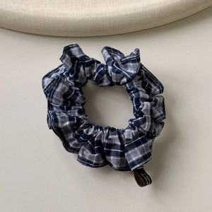 Vue détaillée du chouchou en tissu à carreaux bleu et blanc avec étiquette tissée