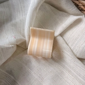 Close-up of a square cream acetate hair claw clip with marble texture on linen fabric