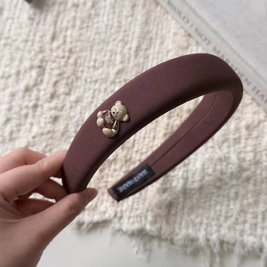 Gros plan d'un serre-tête en tissu marron avec un petit ours en peluche et étiquette faite main