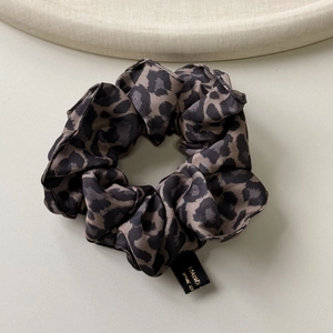 Détail d'un chouchou léopard en soie avec texture satinée lisse et étiquette noire fine