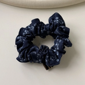 Gros plan d'un chouchou bleu foncé à fleurs et carreaux avec étiquette tissée