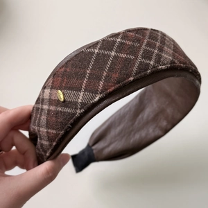 Detail of retro brown plaid headband featuring high-quality wool fabric and gold Love emblem
