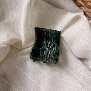Detail of marble pattern acetate hair claw clip on a soft textured linen surface